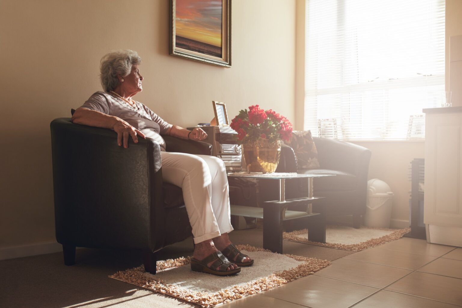 Senior woman sitting alone on a chair at home.
